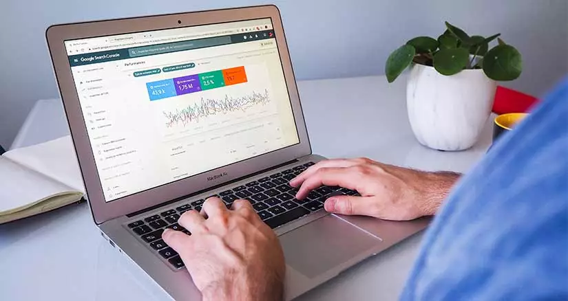 Man using Google Search Console on a white MacBook on a work desk